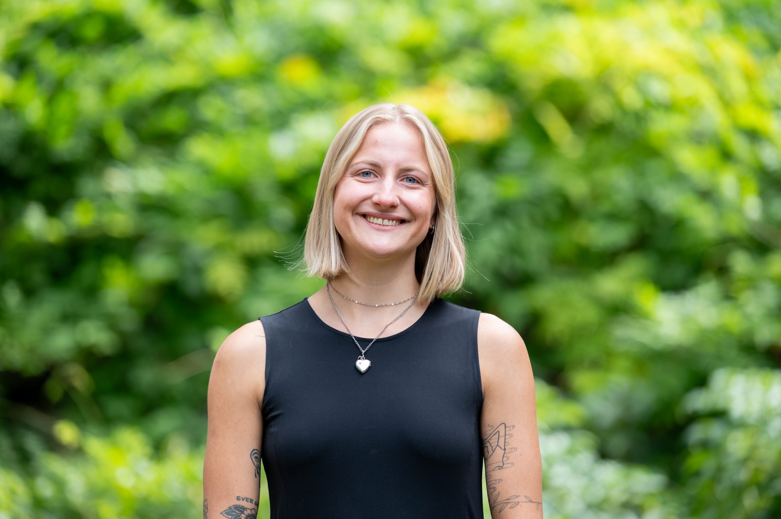 Headshot of woman smiling in front of leafy background