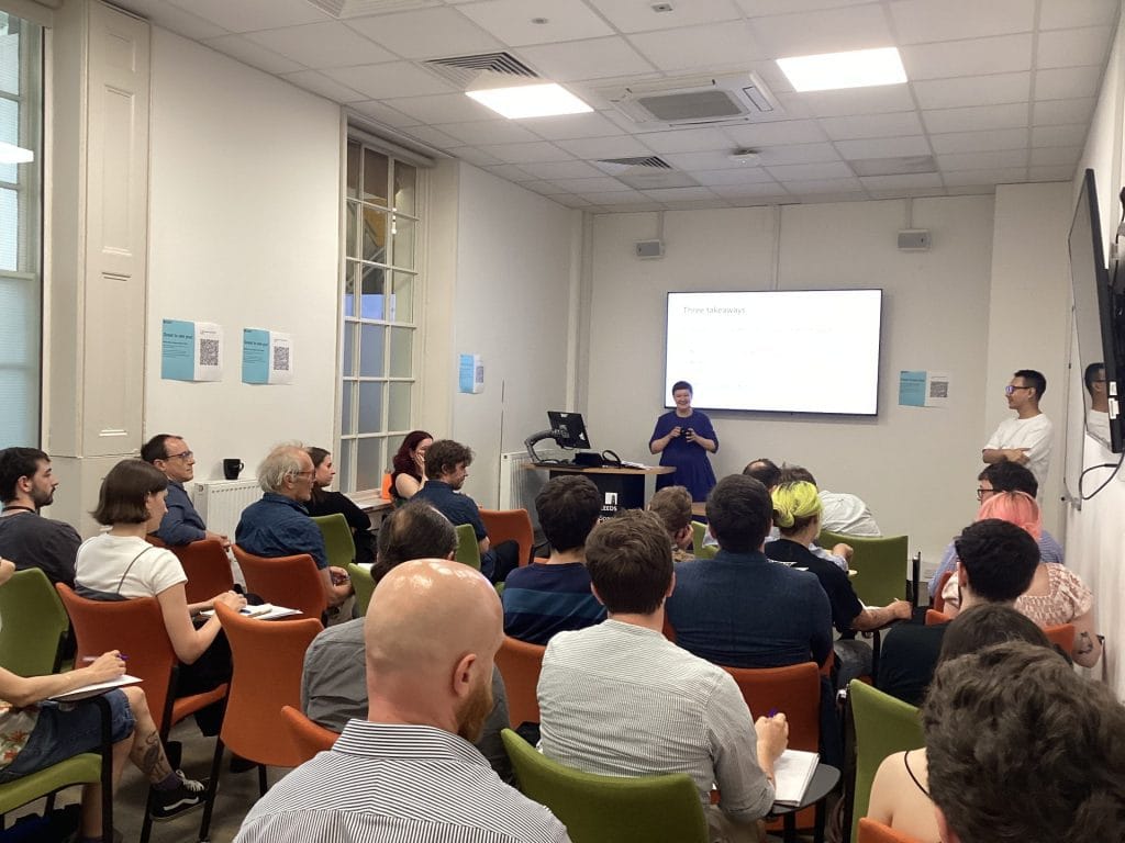 A group of people listening to a speaker at the front of the room