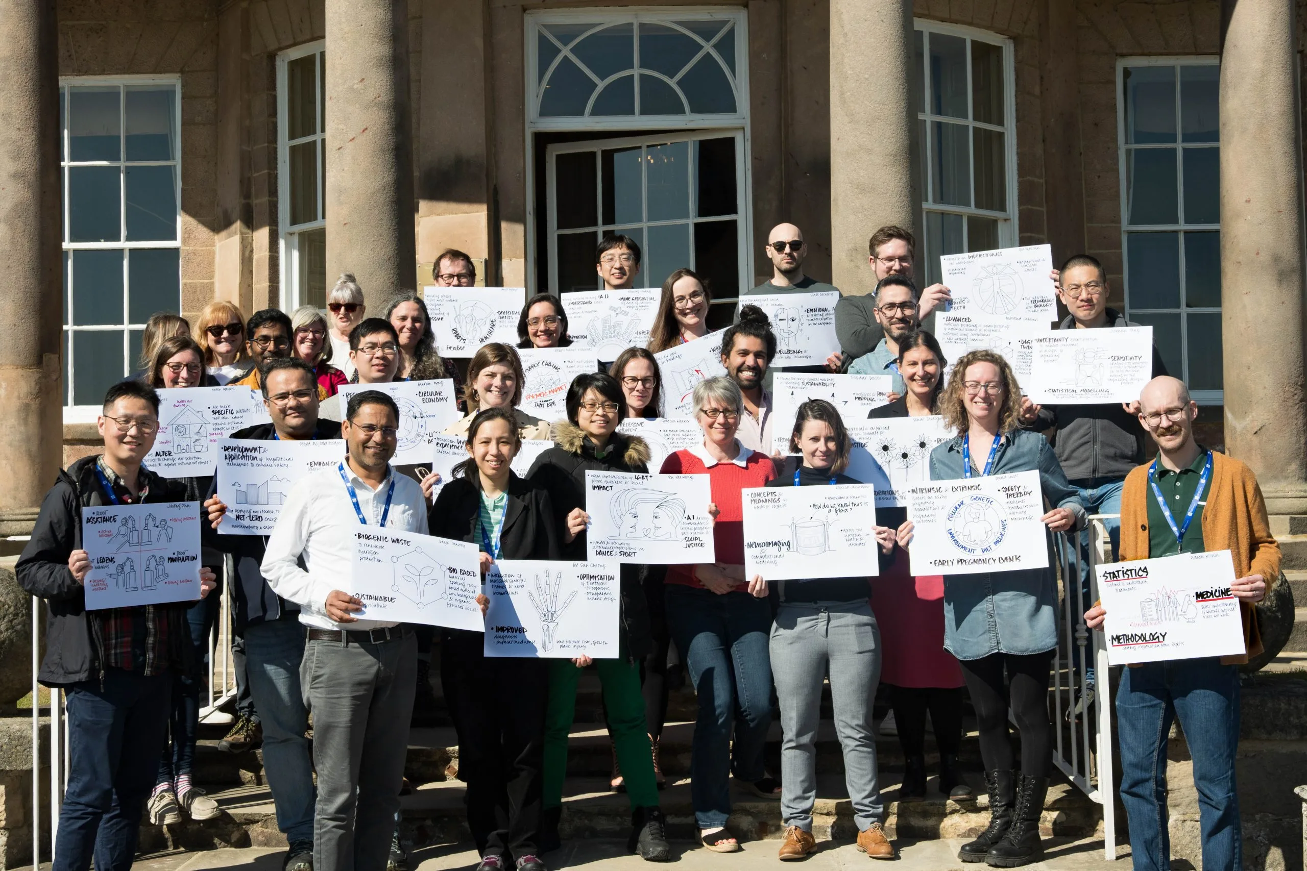 Participants from the Crucible programme in a group holding placards