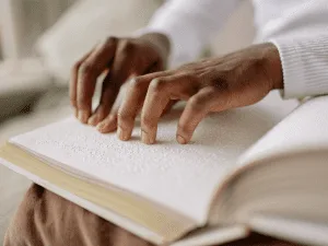 Hands reading braille from a book