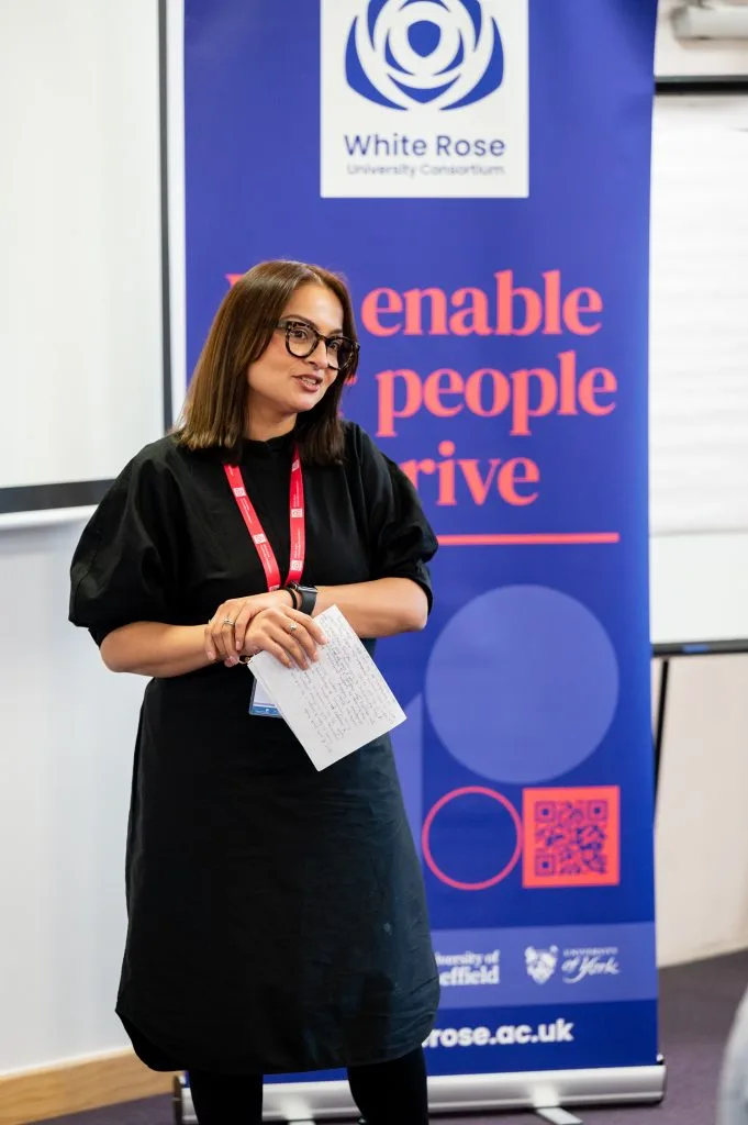 A speaker standing in front of a White Rose banner