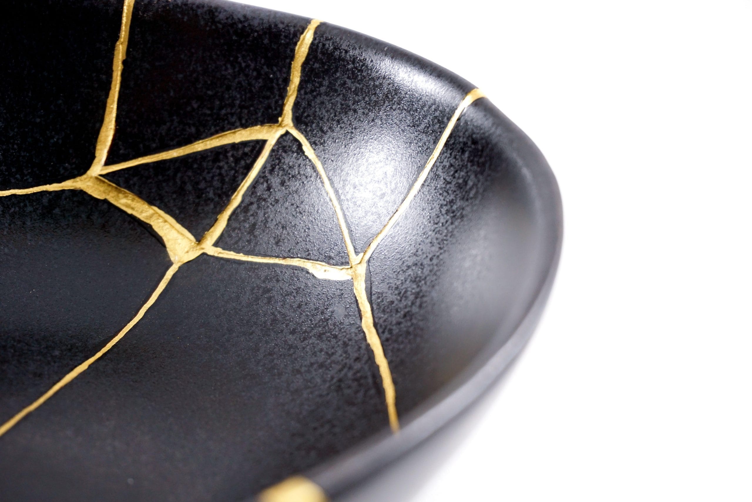 Image of a black bowl restored using the Japanese kintsugi gold technique