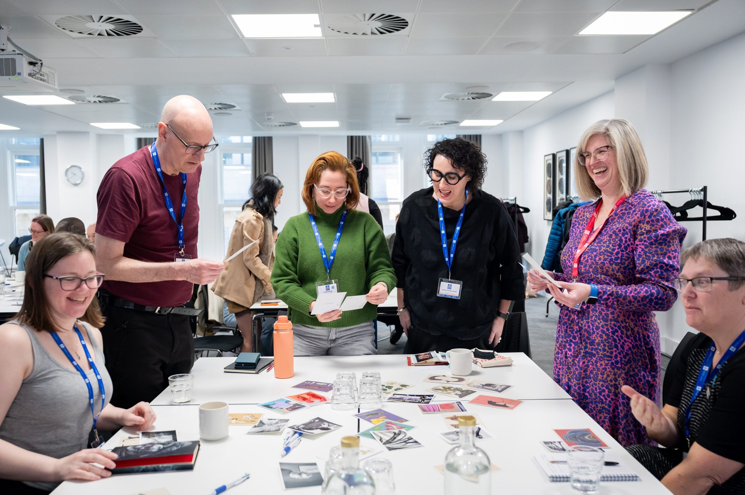 Group of six people standing around a table covered in image cards