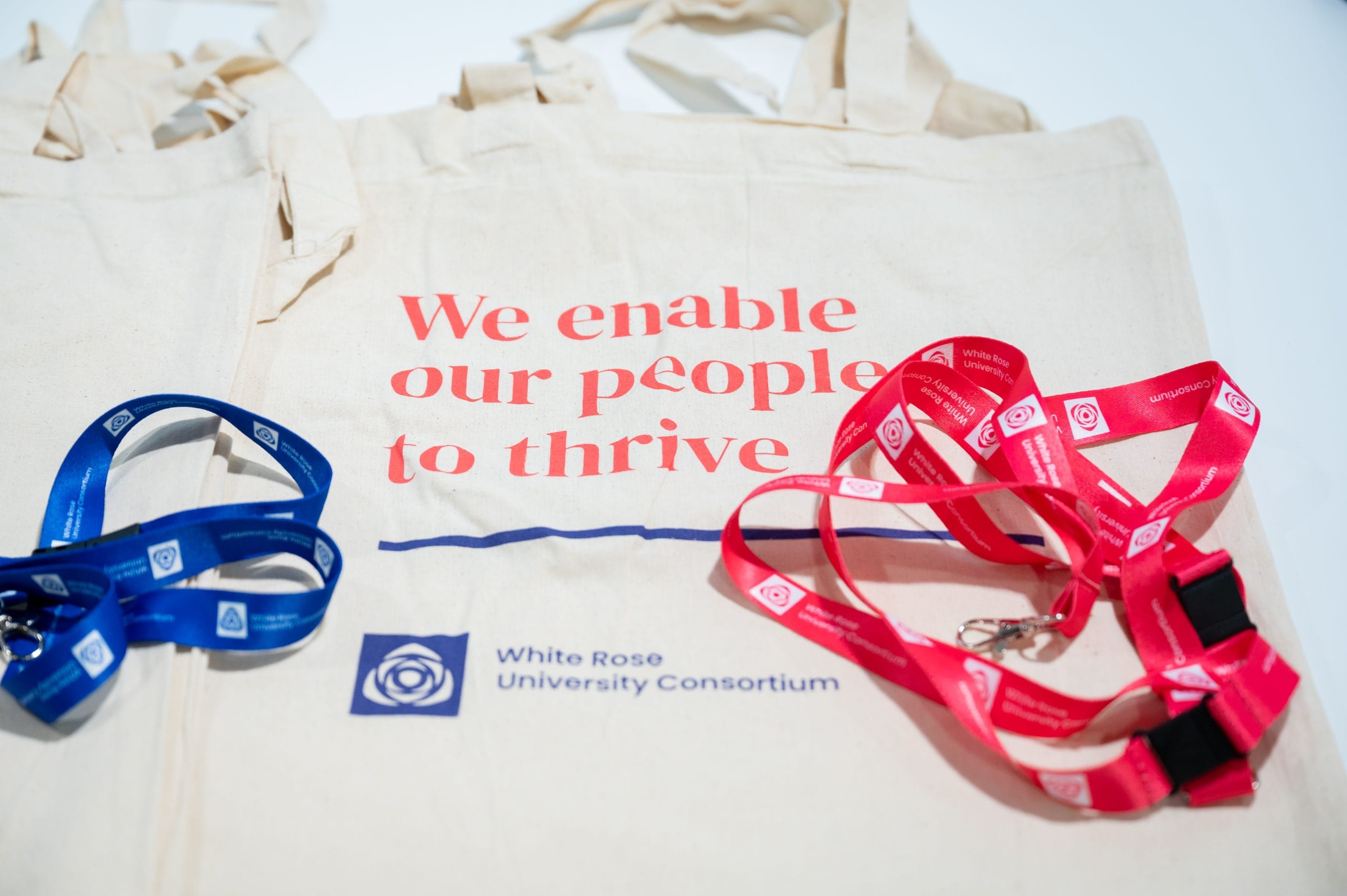 Bag with text 'We enable our people to thrive' with a pink and navy lanyard.