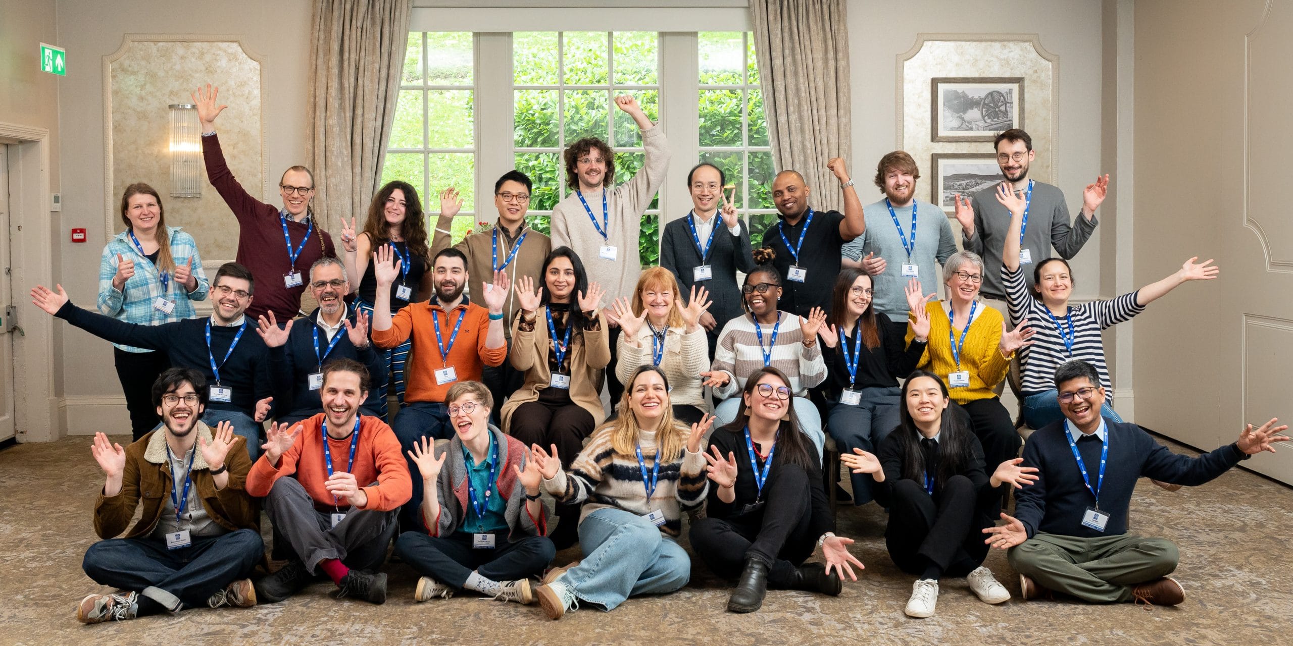Group of around 20 people with lanyards smiling at camera