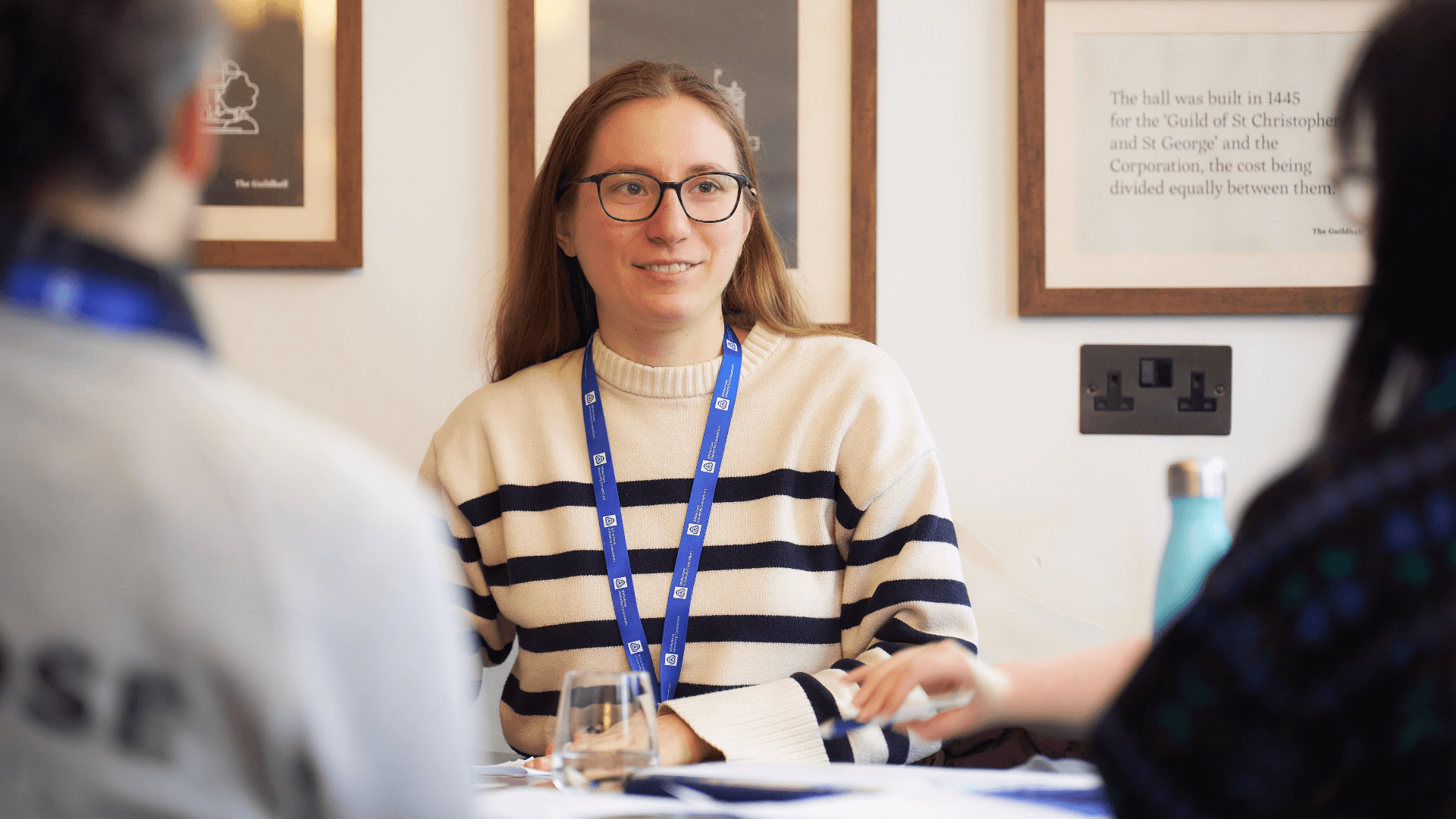 Women in White Rose University Consortium lanyard at table with two people facing away from camera