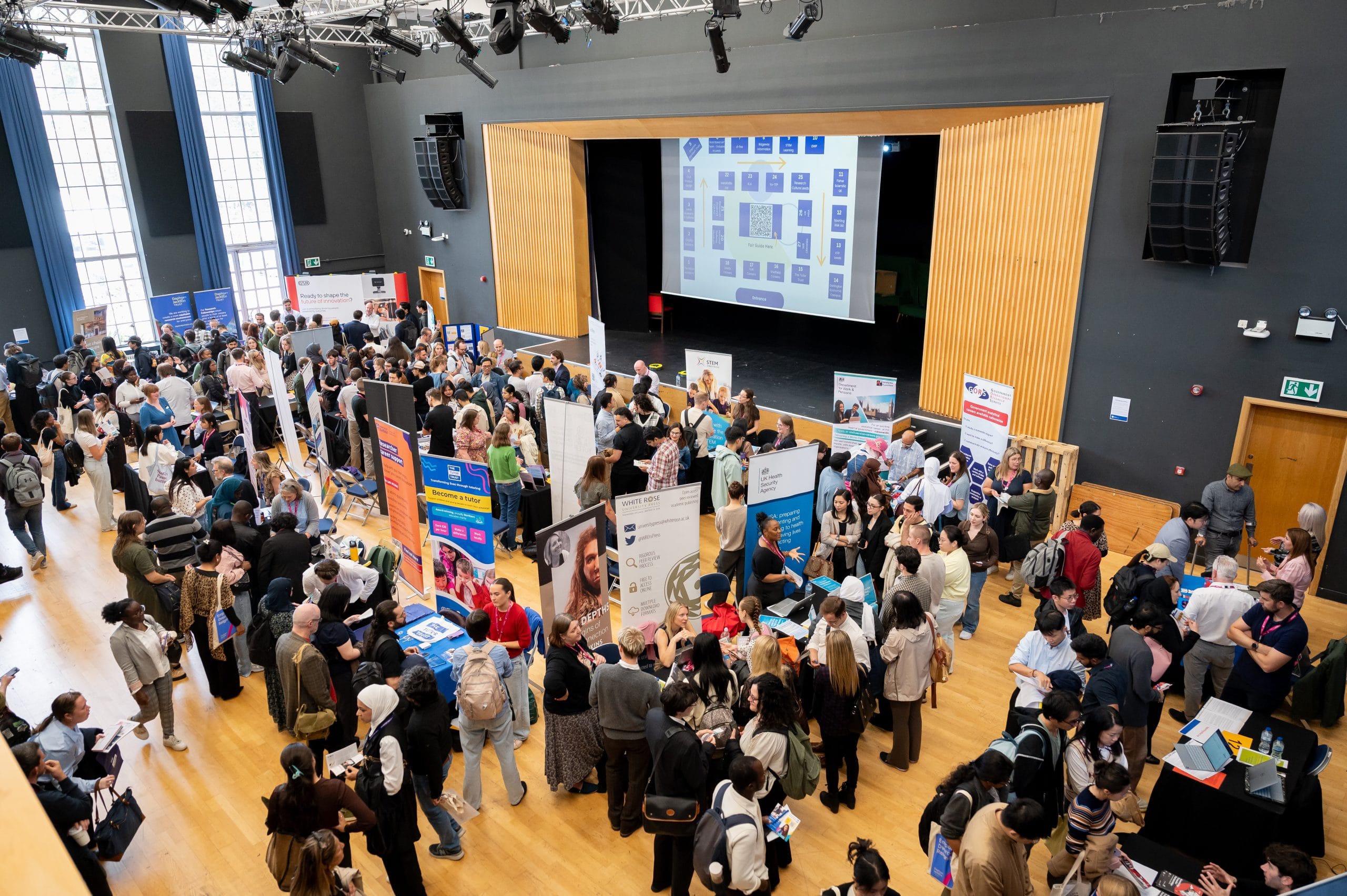 Overhead shot of a busy hall with banners, tables, and many people talking