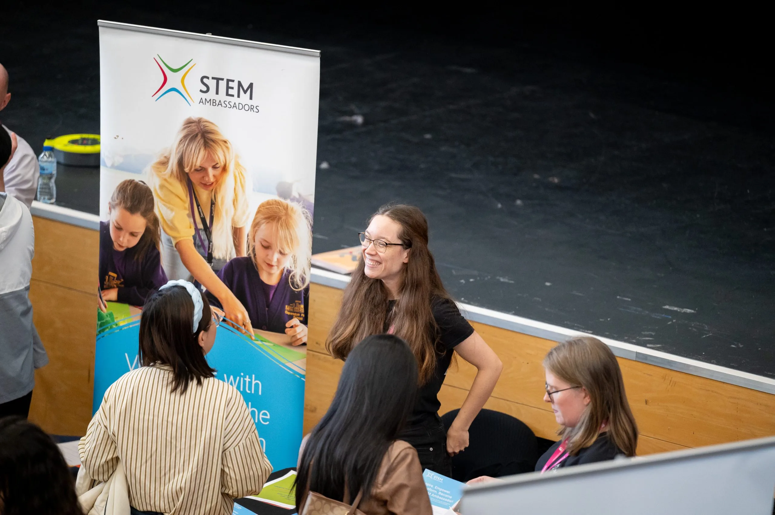 Woman smiling in front of a banner that says 'STEM learning ambassador'