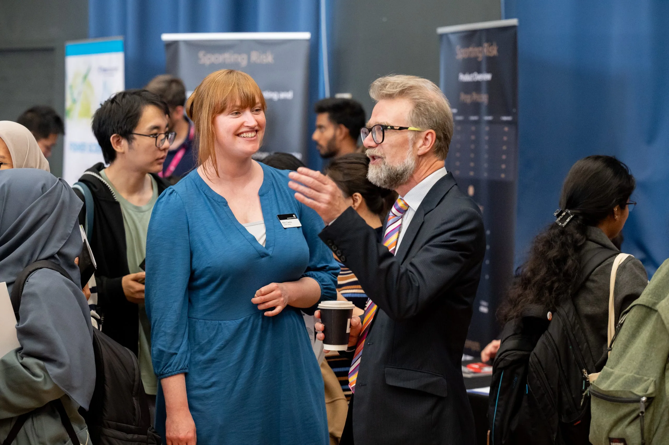 woman with blue dress talks to a man in a suit