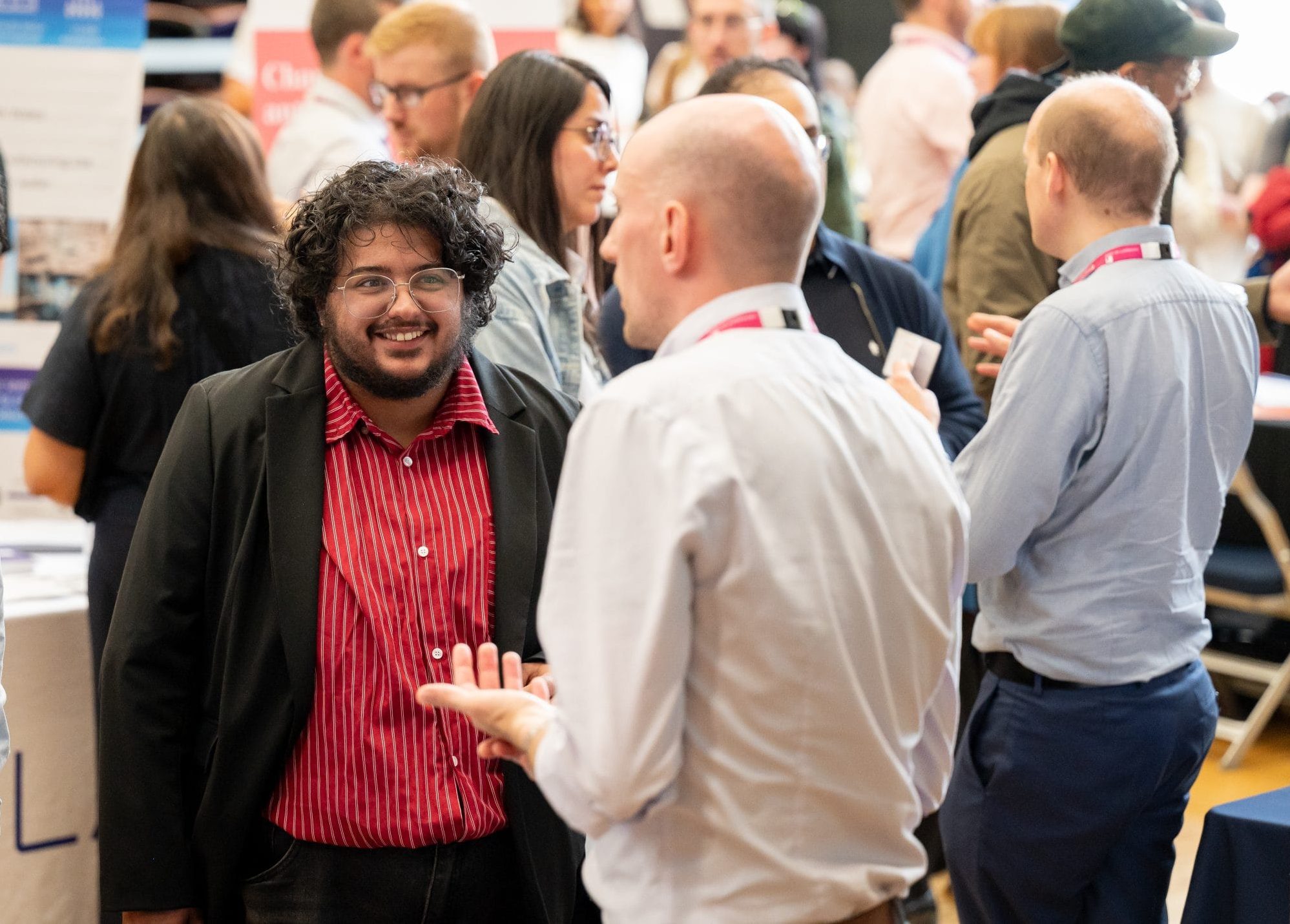 crowded room with two people talking to eachother and smiling