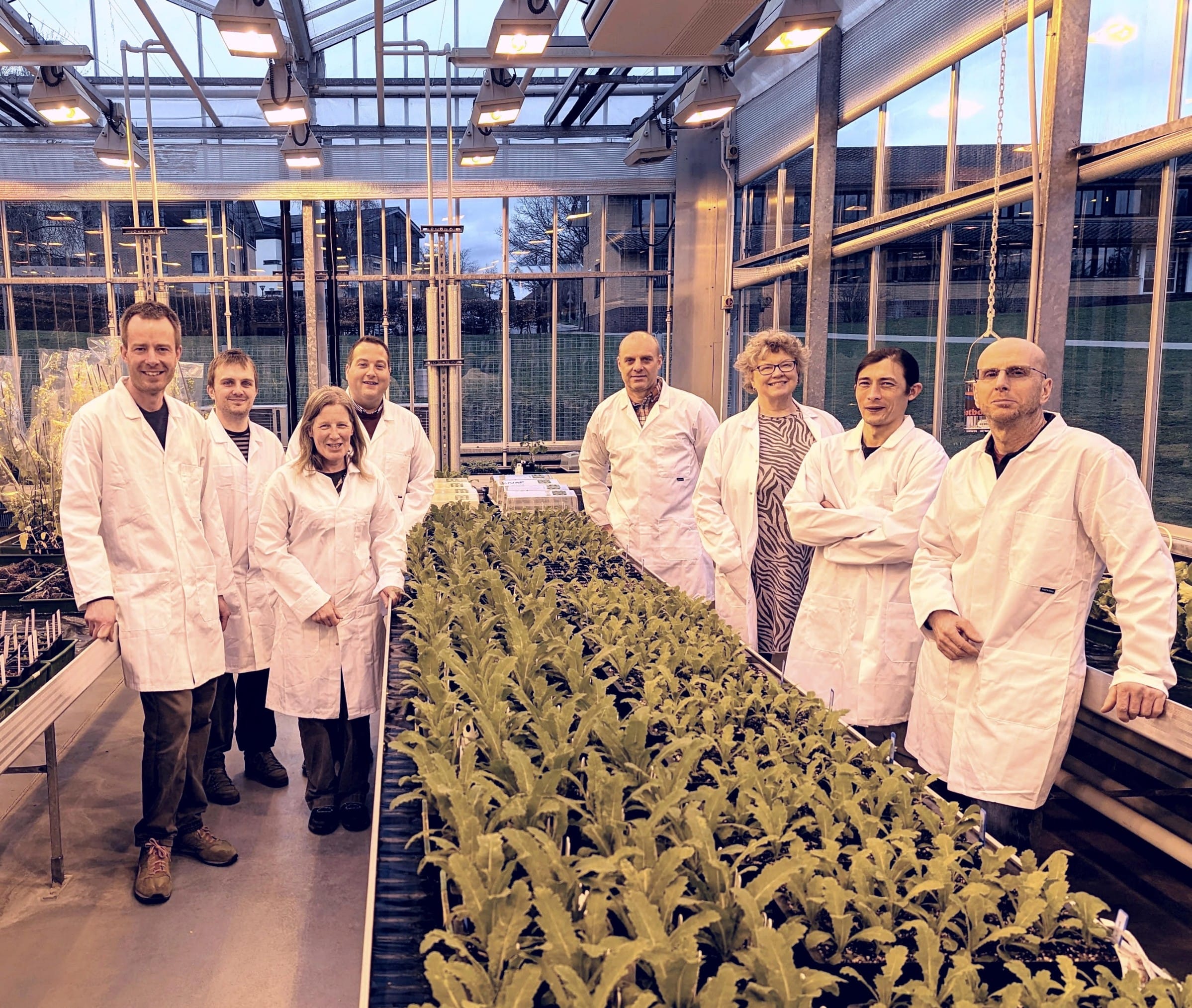 group of people in lab coats in a greenhouse with plants